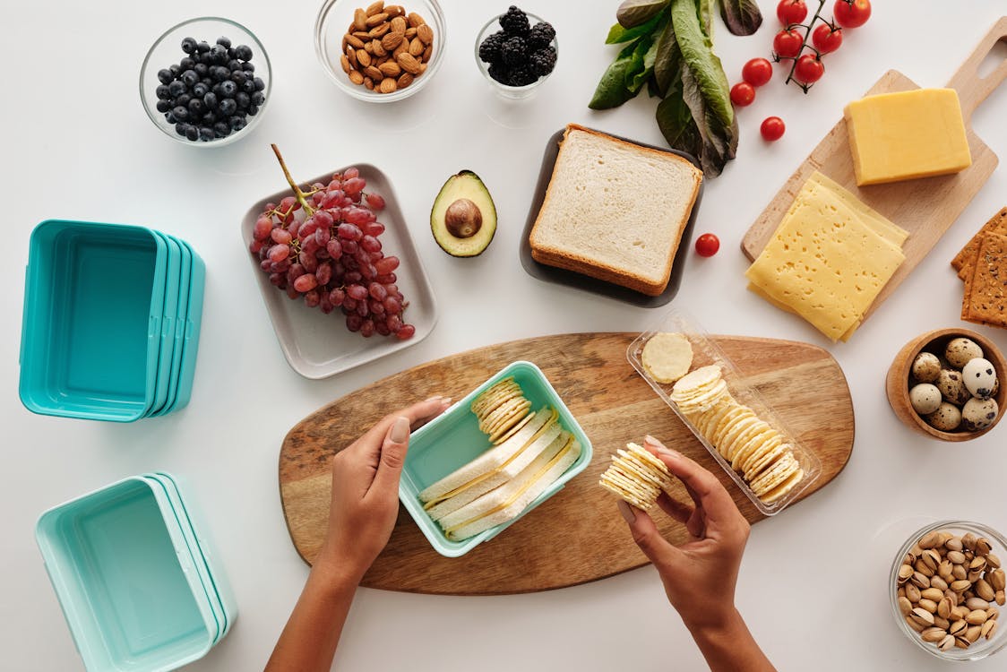 Free Top view of preparing a healthy lunch with fruits, cheese, and crackers, showcasing fresh ingredients and a vibrant lifestyle. Stock Photo