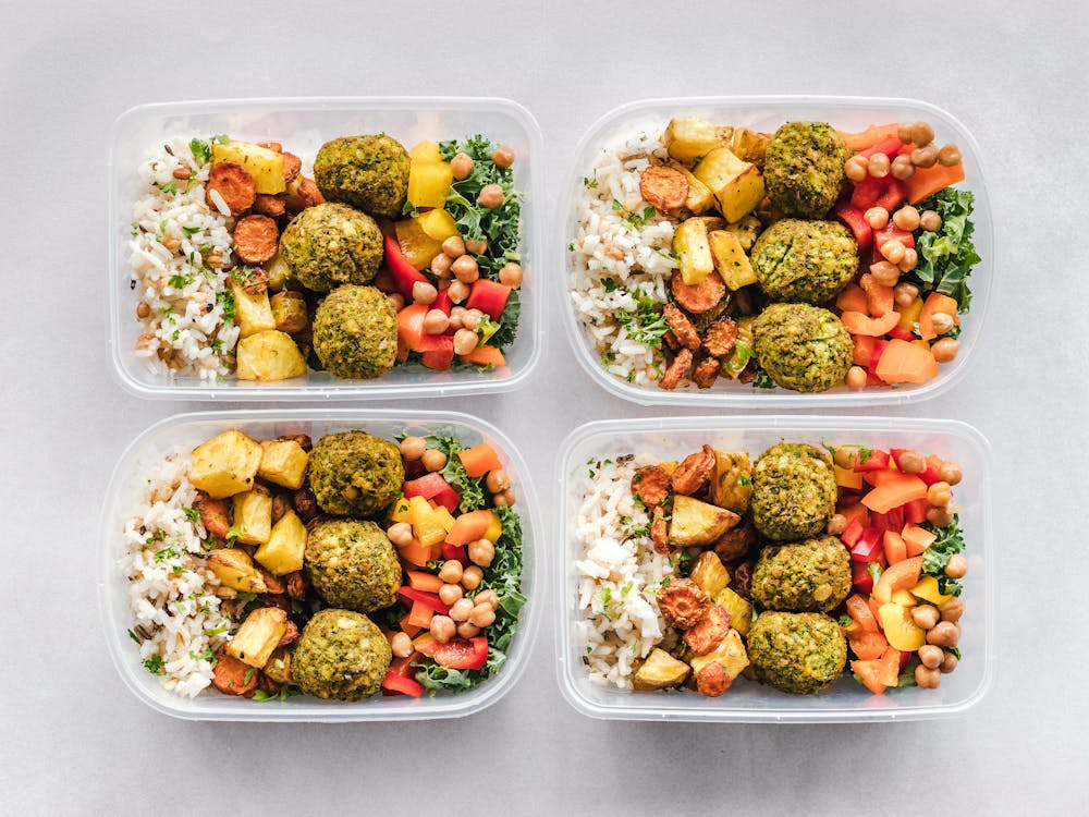 Free Colorful meal prep containers with falafel, chickpeas, rice, and vegetables for a healthy lifestyle. Stock Photo